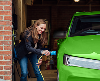 Woman charging electric vehicle at home